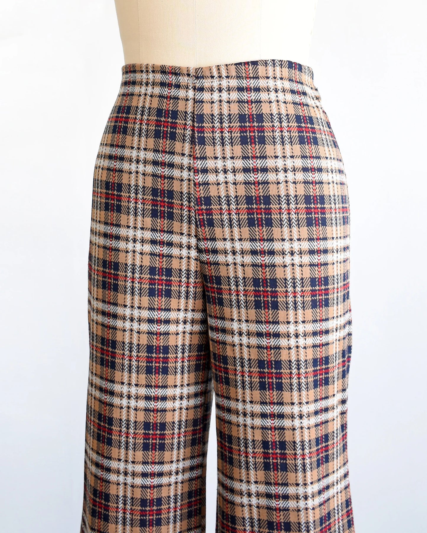side front view of a pair of vintage 70s brown, blue, red, black, and white plaid pants with flared bottoms on a dress form.