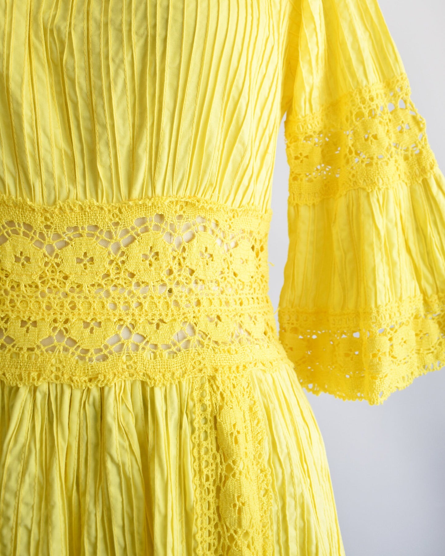 Close up of the waistline that shows the open crochet trim, along with the pin tuck pleats