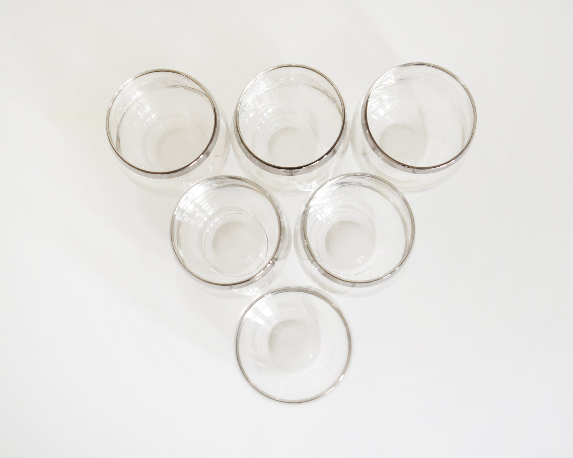 Overhead shot of a set of 6 vintage 60s sliver rim tumblers that have an elongated roly poly shape