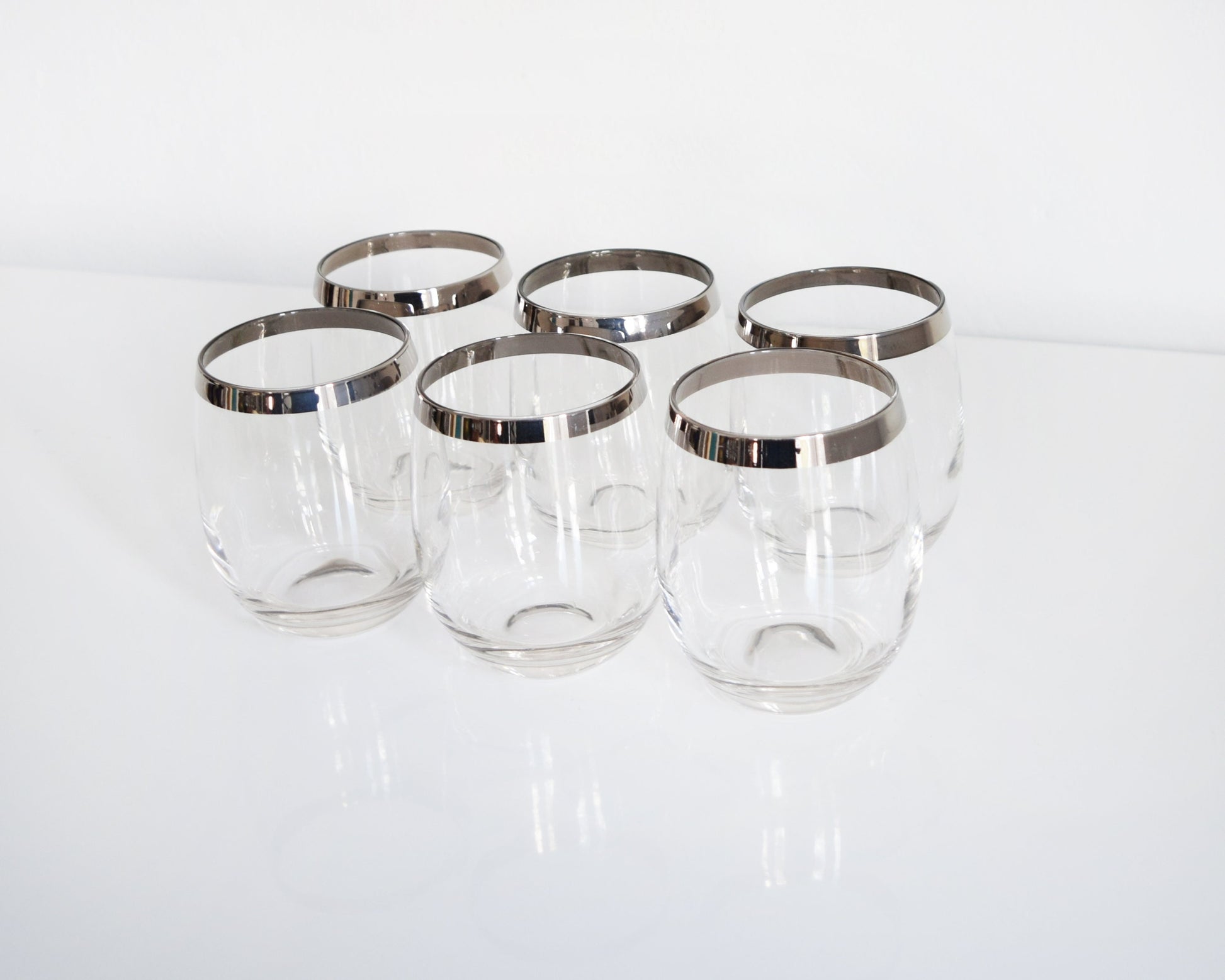 A set of 6 vintage 60s sliver rim tumblers that have an elongated roly poly shape