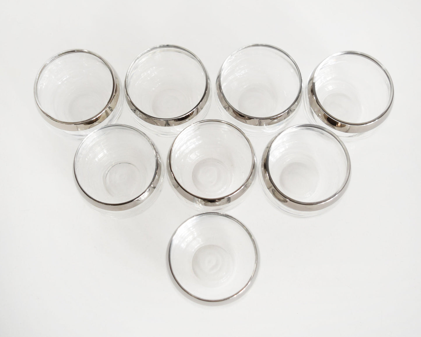 overhead view of eight silver rim roly poly glasses on a table