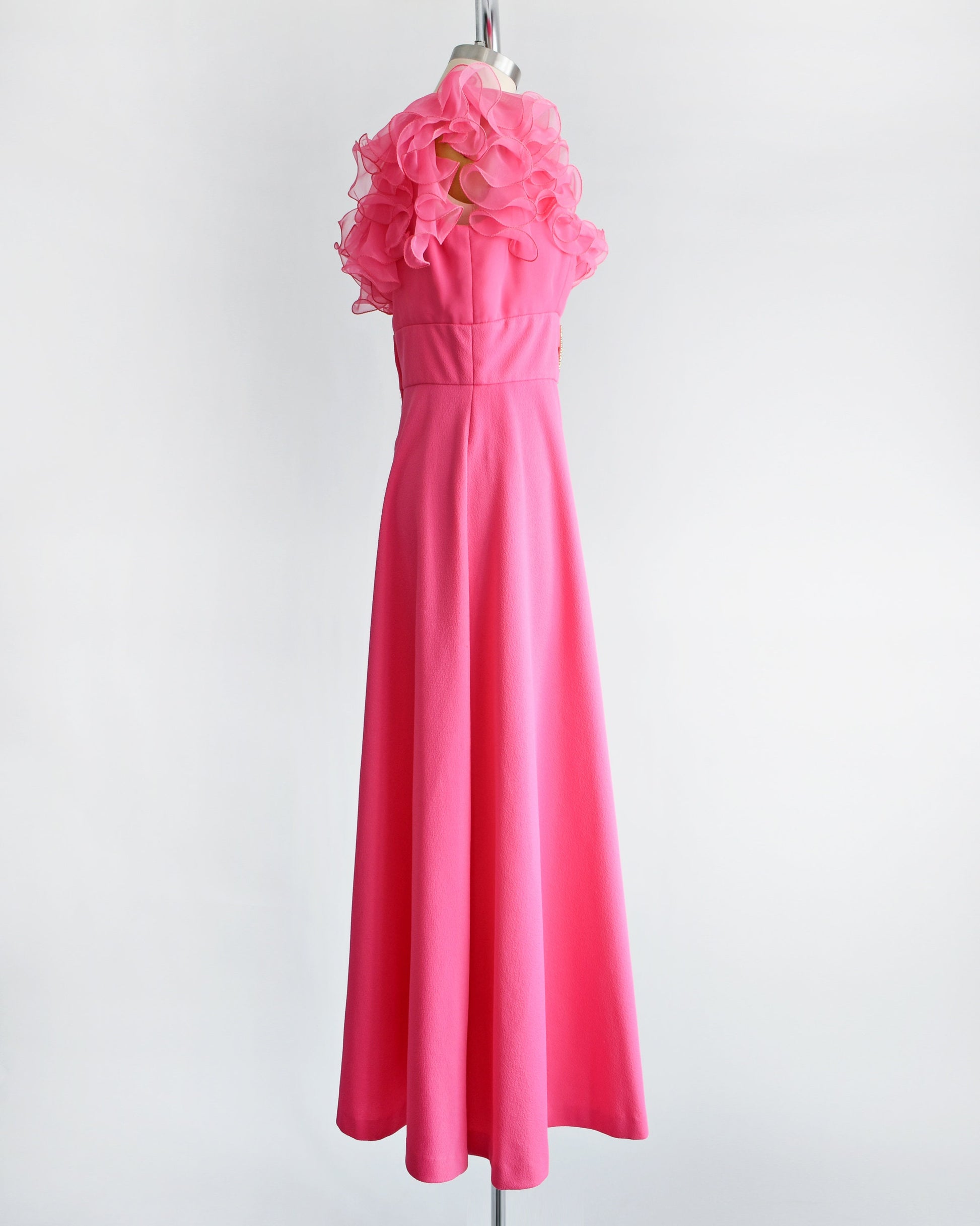 Side view of a vintage 1970s hot pink maxi dress that has a ruffled neckline