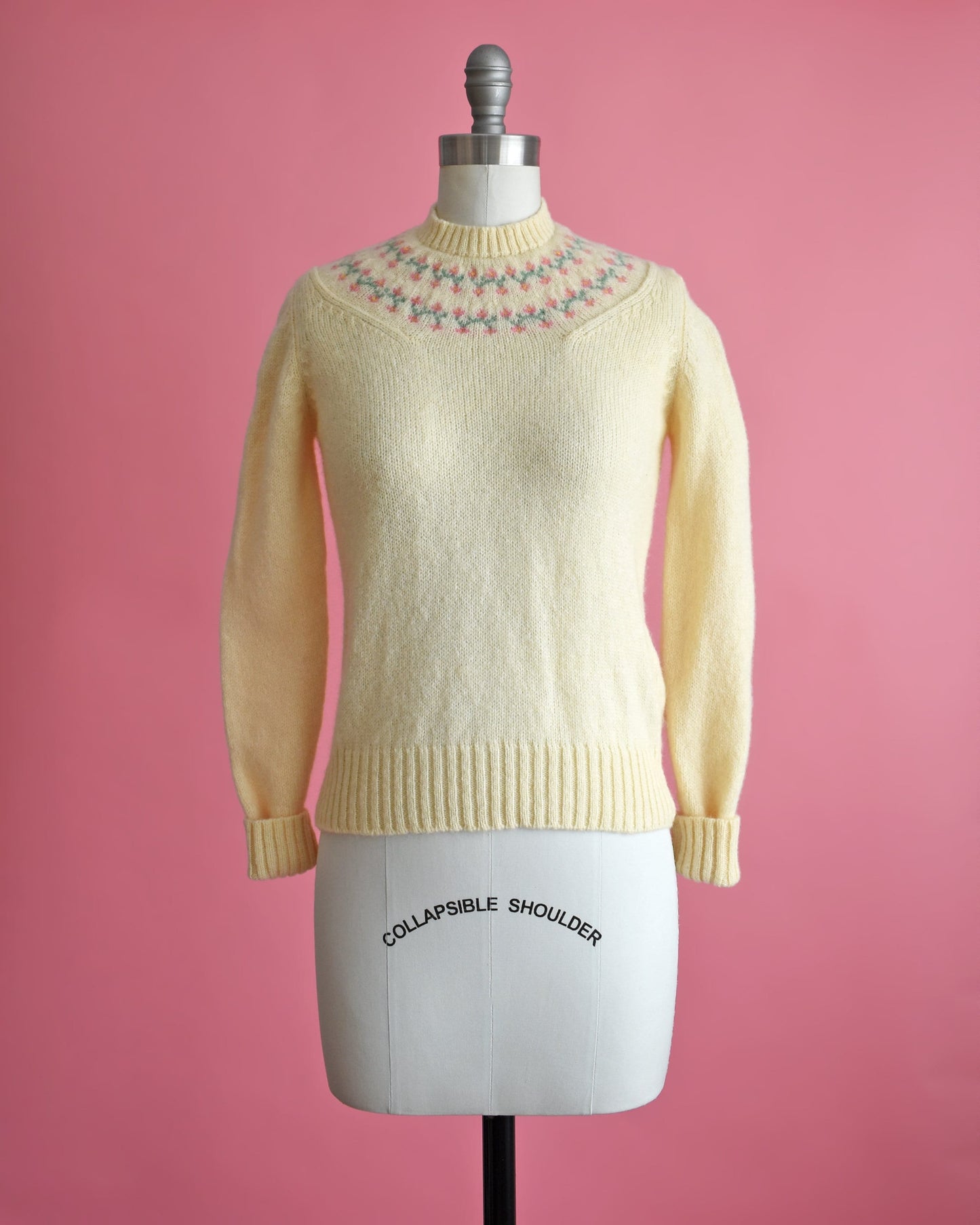 A vintage 80s cream sweater with pink and green flowers around the collar.