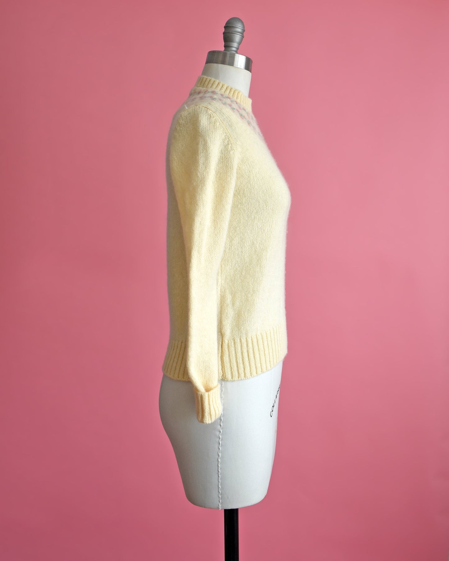 Side view of a vintage 80s cream sweater with pink and green flowers around the collar.