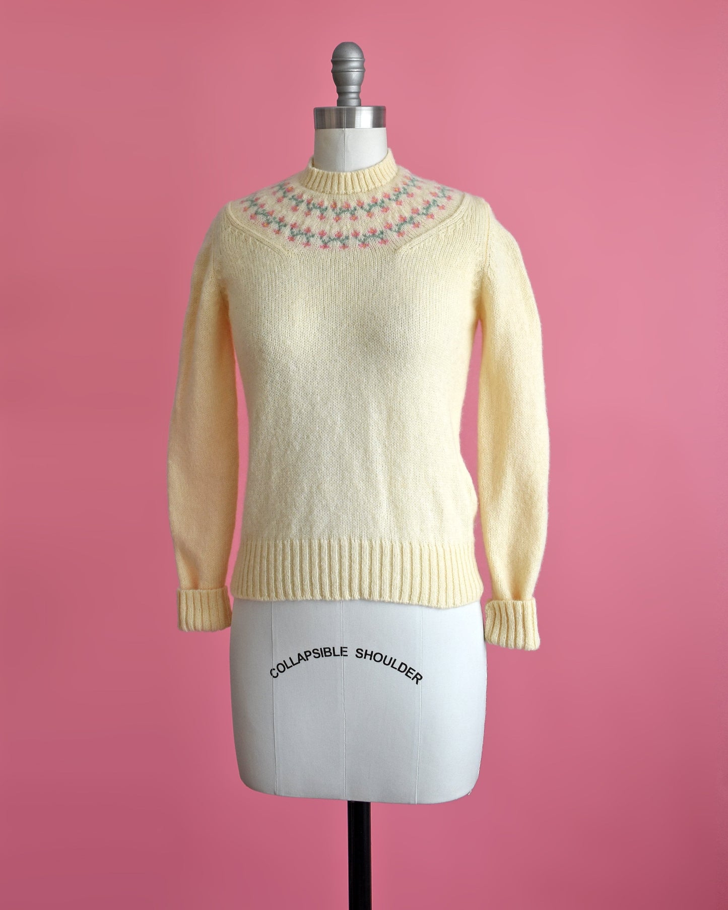 Side front view of a vintage 80s cream sweater with pink and green flowers around the collar.