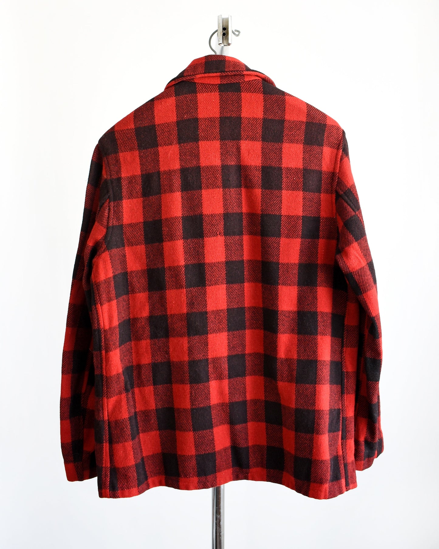 Back view of a A photo of a vintage 40s red and black plaid jacket. The jacket is modeled on a hanger.