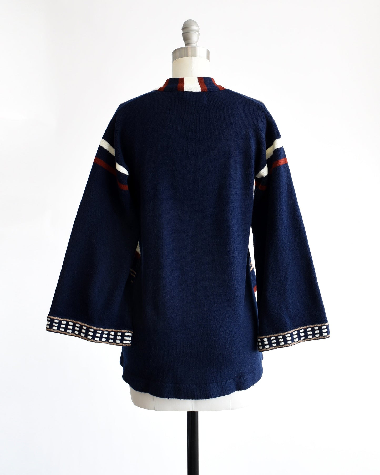 Back view of a vintage 70s navy blue, tan, reddish brown, and white striped bell sleeve open cardigan on a dress form.