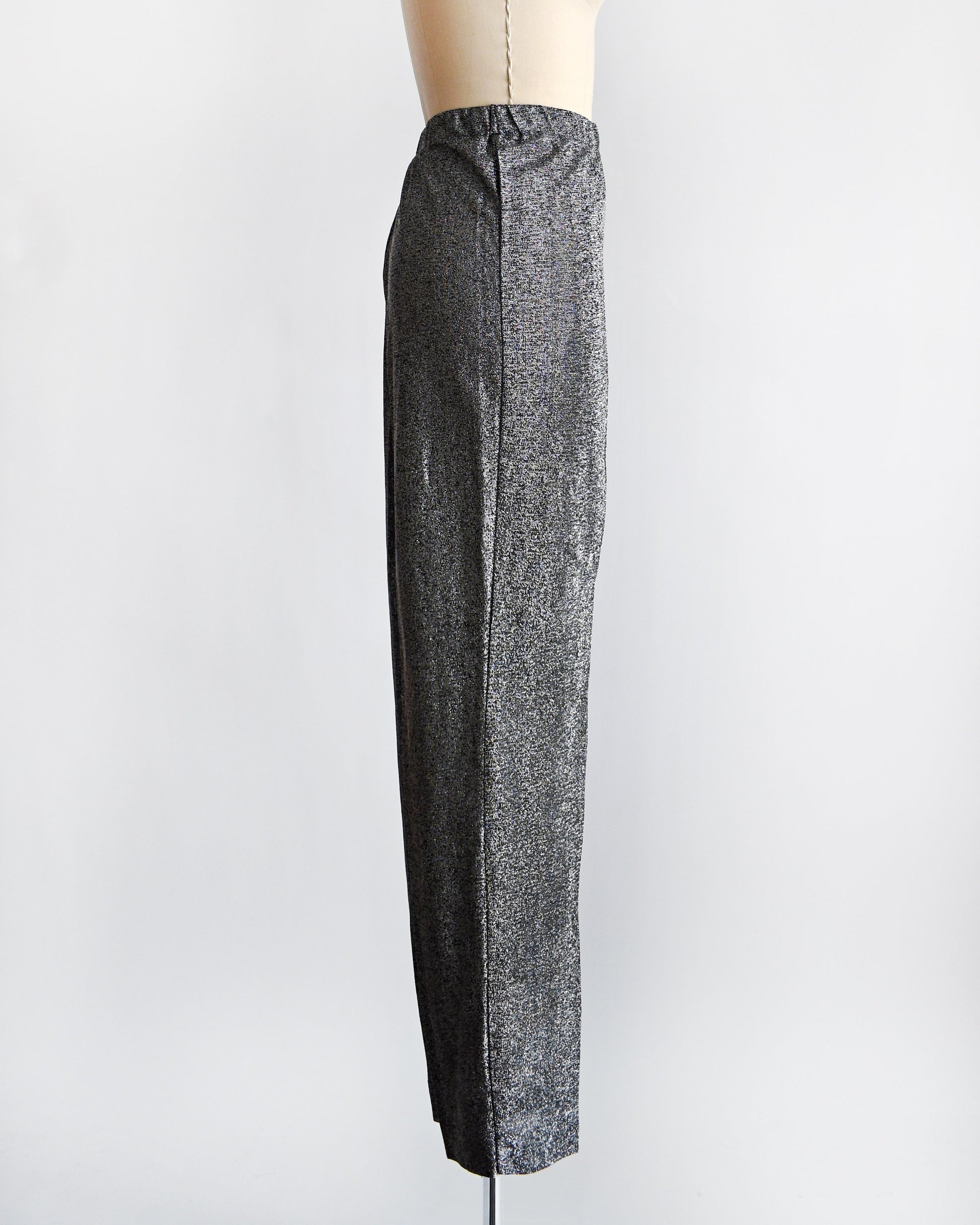 Side view of a vintage pair of 70s silver and black metallic pants on a dress form.
