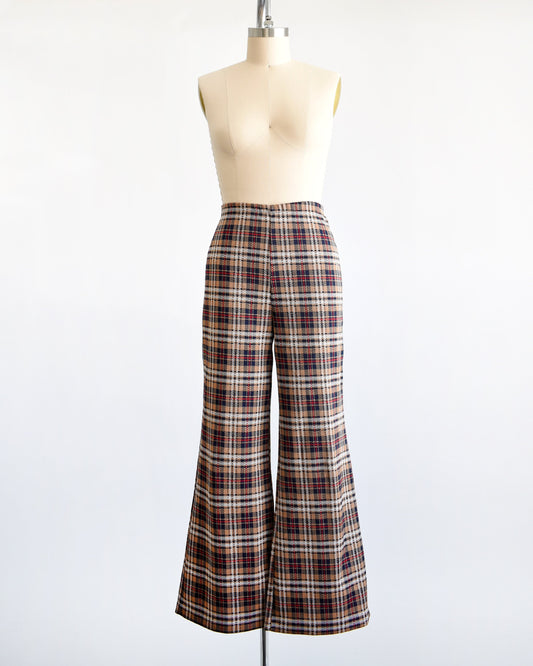 A pair of vintage 70s brown, blue, red, black, and white plaid pants with flared bottoms on a dress form.