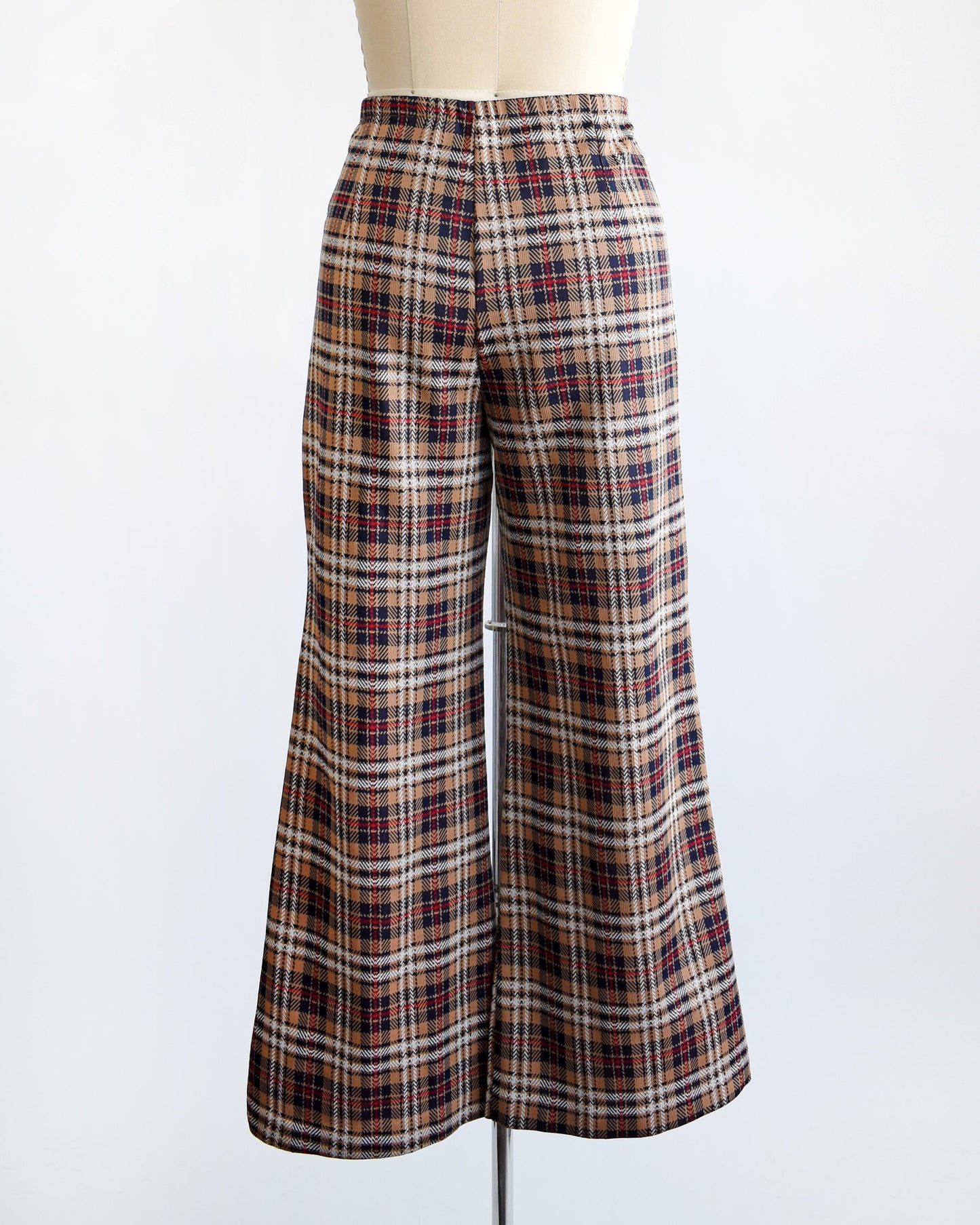 Back view of a pair of vintage 70s brown, blue, red, black, and white plaid pants with flared bottoms on a dress form.
