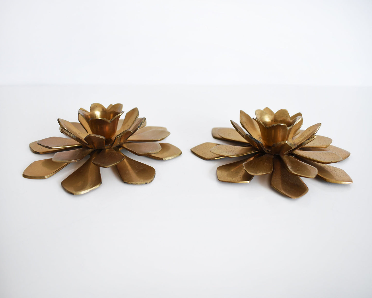 Overhead side view of a pair of vintage brass lotus candle holders