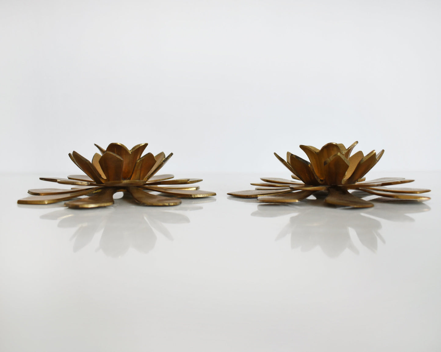 Side view of a pair of vintage brass lotus candle holders