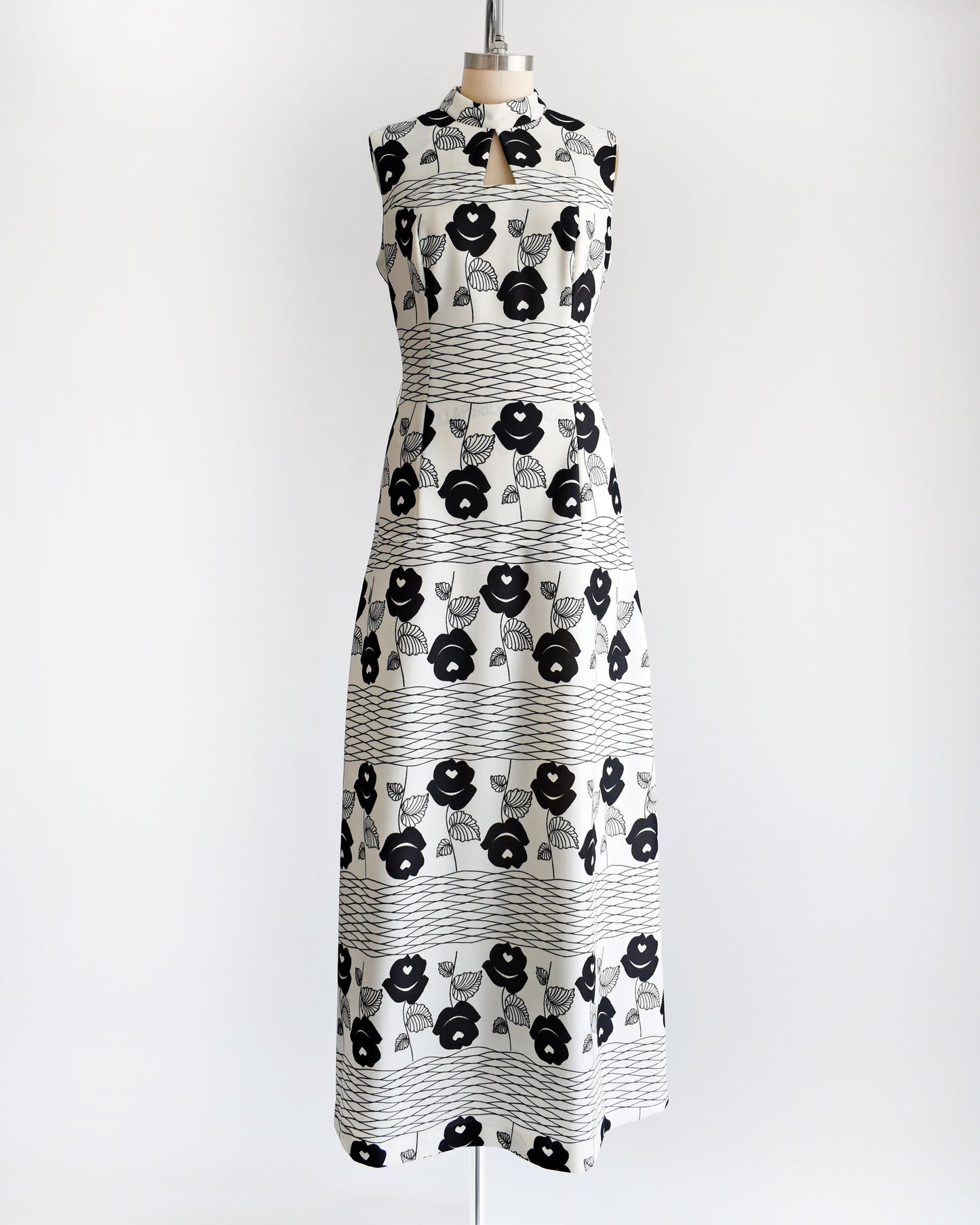 A vintage 70s white maxi dress black floral print with wavy horizontal lines. Dress is shown without the belt