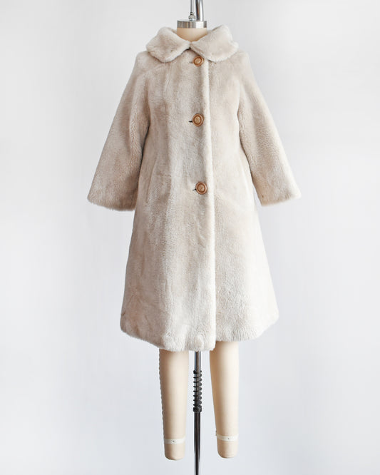 A vintage 1960s plush cream faux fur coat that features a Peter Pan style collar and three large buttons down the front