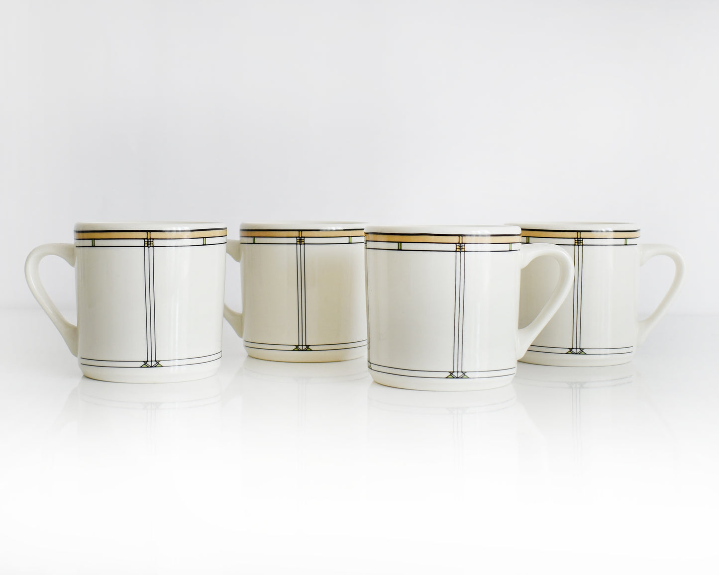 Set of four vintage Frank Lloyd Wright Martin House white mugs with gold trim on a white background