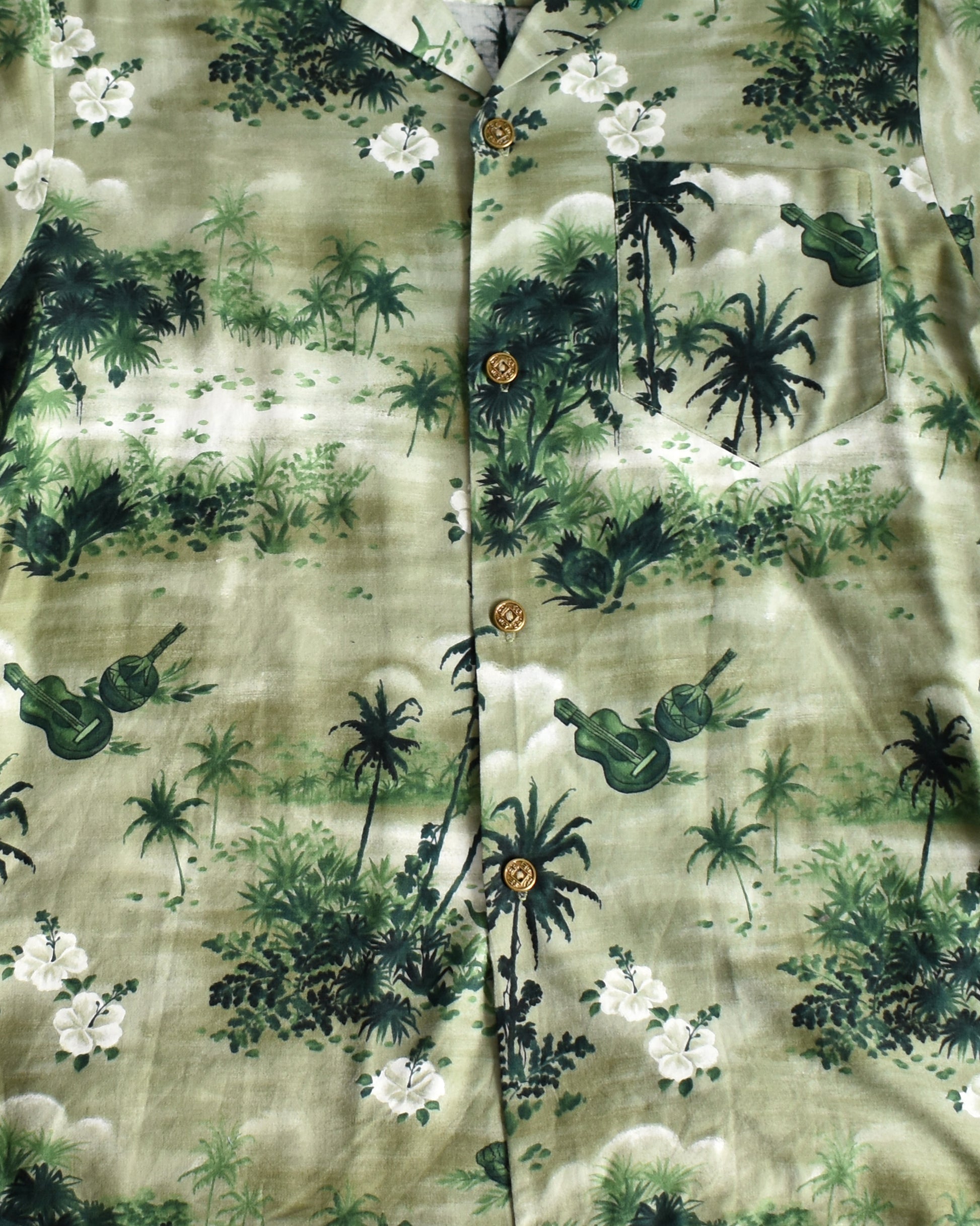 close up of the tropical print on a vintage 1950s green Hawaiian shirt by Royal Hawaiian on a white background