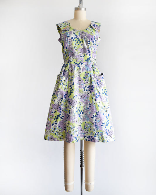A vintage 1950s purple, green, blue, and white floral cotton sundress on a dress form