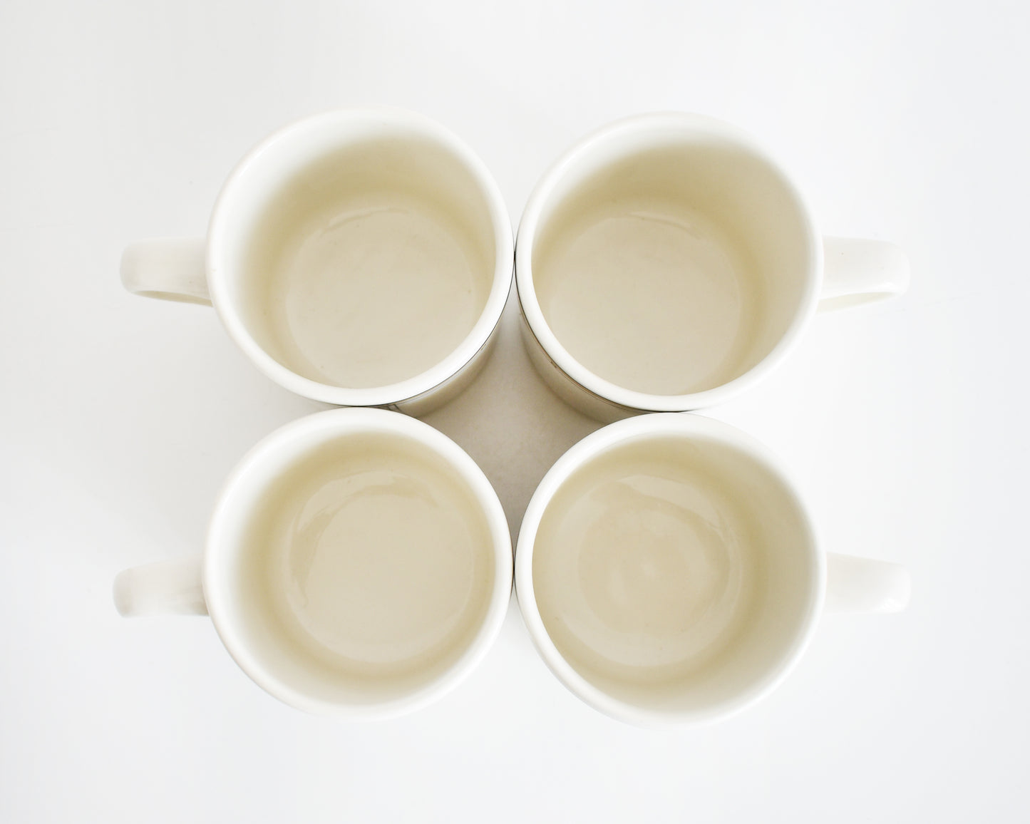 overhead shot of four vintage Frank Lloyd Wright Martin House white mugs with gold trim on a white background