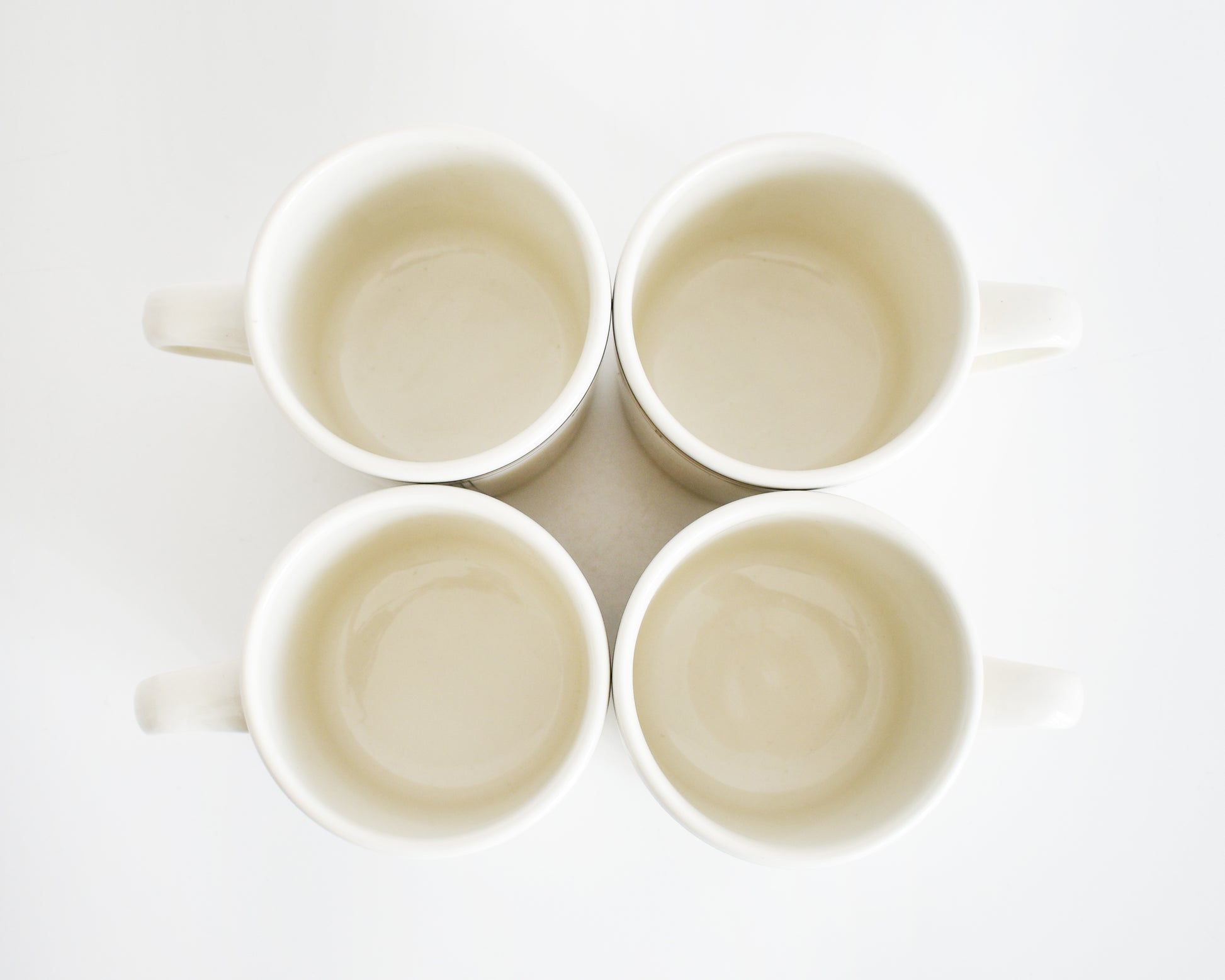 overhead shot of four vintage Frank Lloyd Wright Martin House white mugs with gold trim on a white background