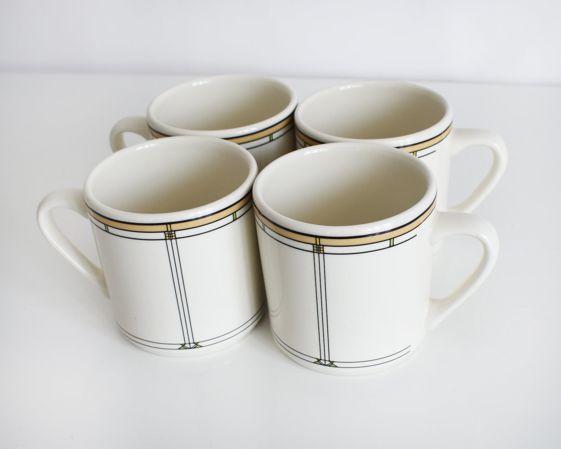 set of four vintage Frank Lloyd Wright Martin House white mugs with gold trim on a white background