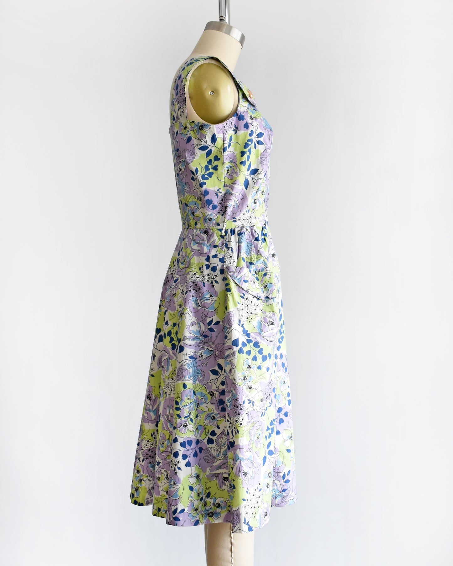 side view of a vintage 1950s purple, green, blue, and white floral cotton sundress on a dress form