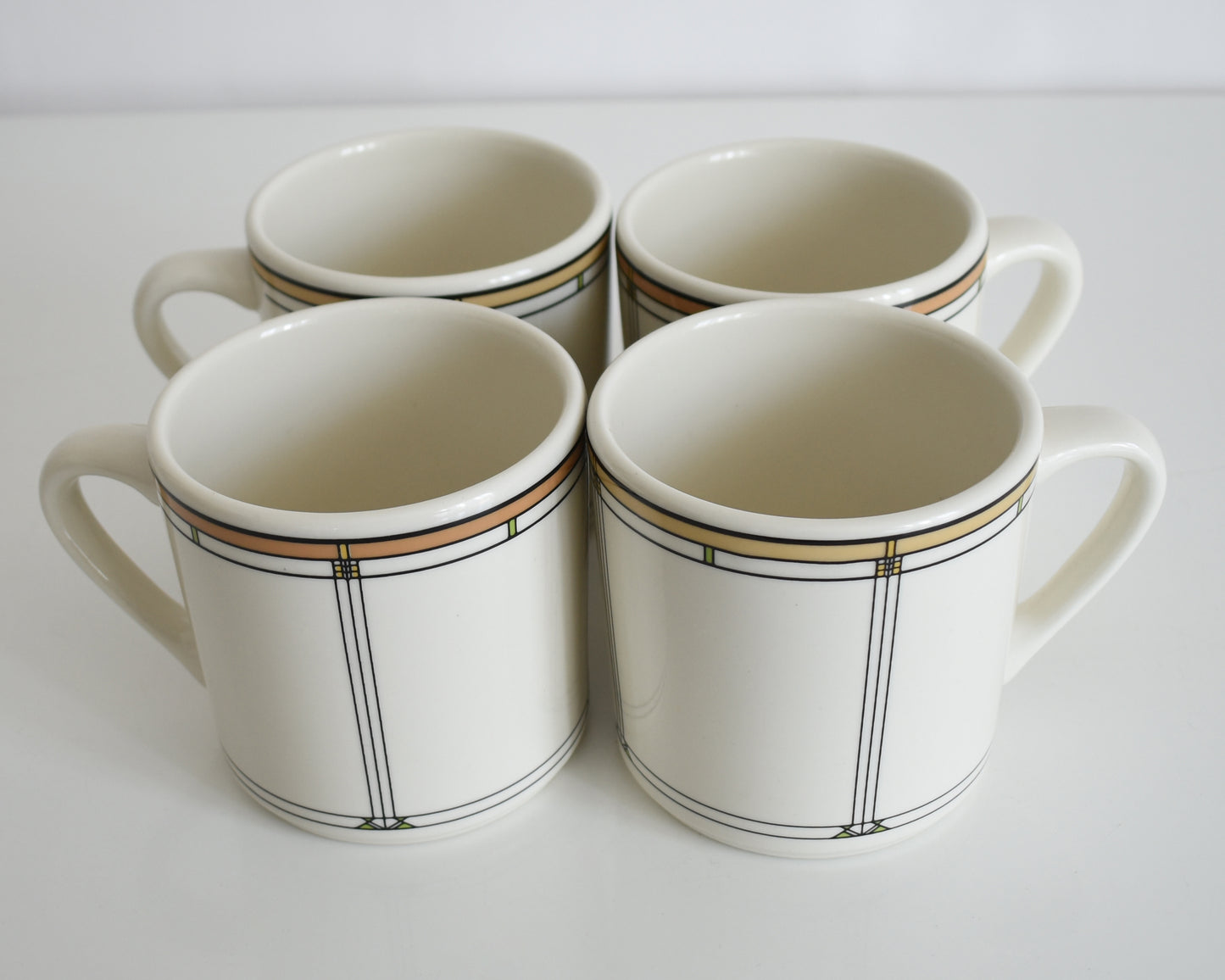  a set of four vintage Frank Lloyd Wright Martin House white mugs with gold trim on a white background