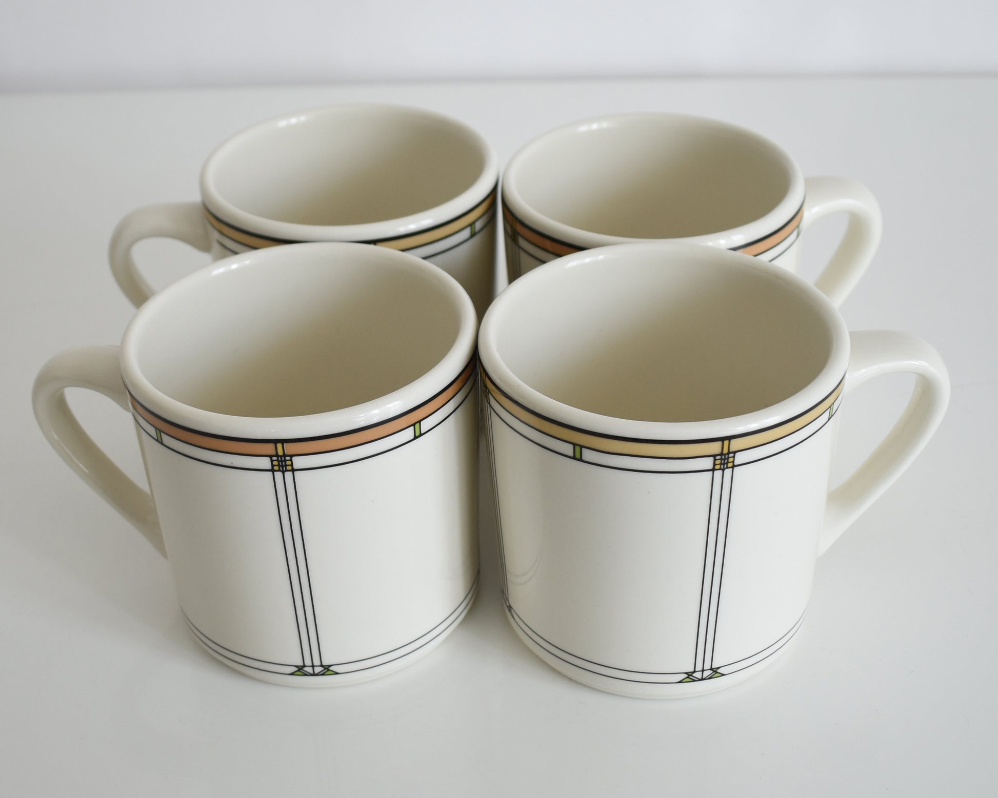  a set of four vintage Frank Lloyd Wright Martin House white mugs with gold trim on a white background