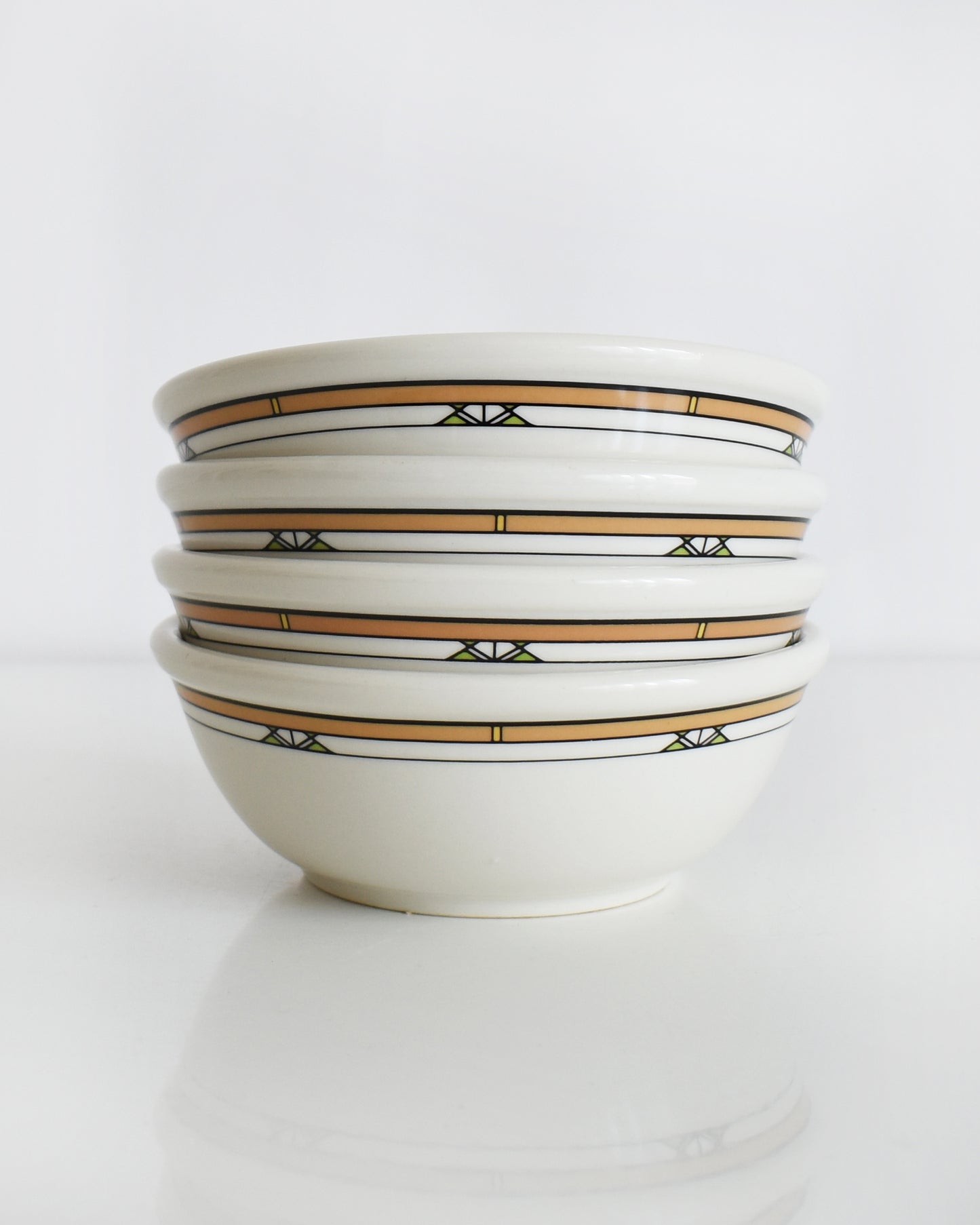 a stack of Frank Lloyd Wright Martin House white bowls with brown geometric patterns on a white background