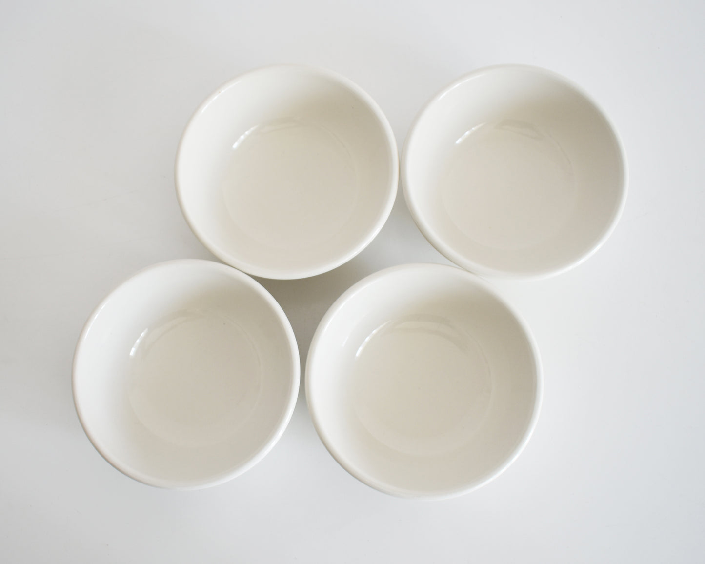 overhead shot of a set of four Frank Lloyd Wright Martin House white bowls with brown geometric patterns on a white background