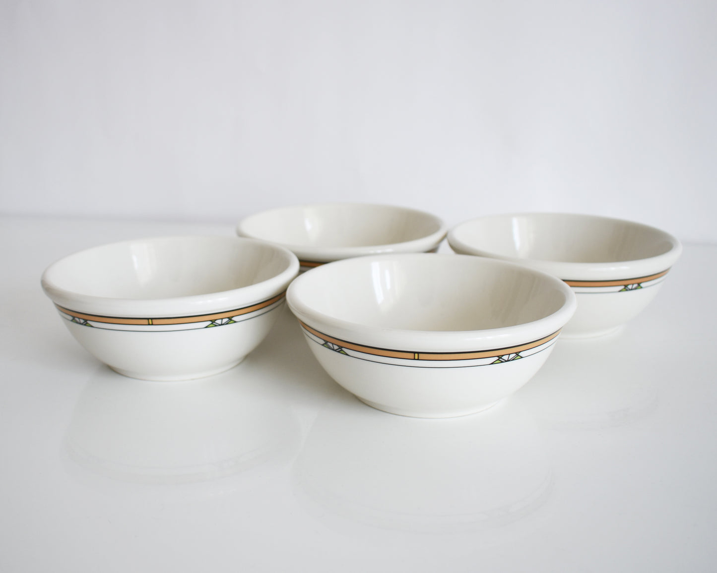 a set of four Frank Lloyd Wright Martin House white bowls with brown geometric patterns on a white background