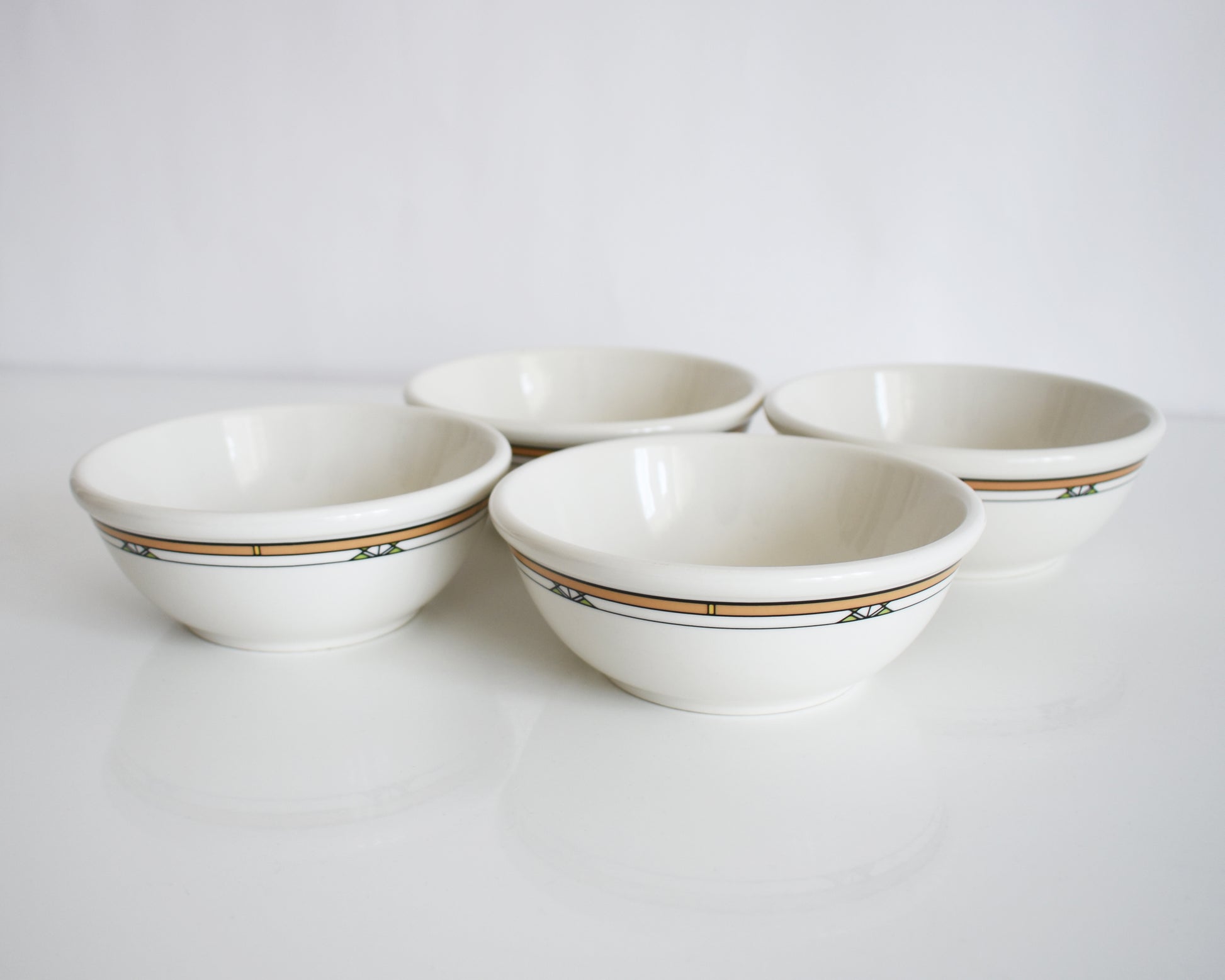 a set of four Frank Lloyd Wright Martin House white bowls with brown geometric patterns on a white background