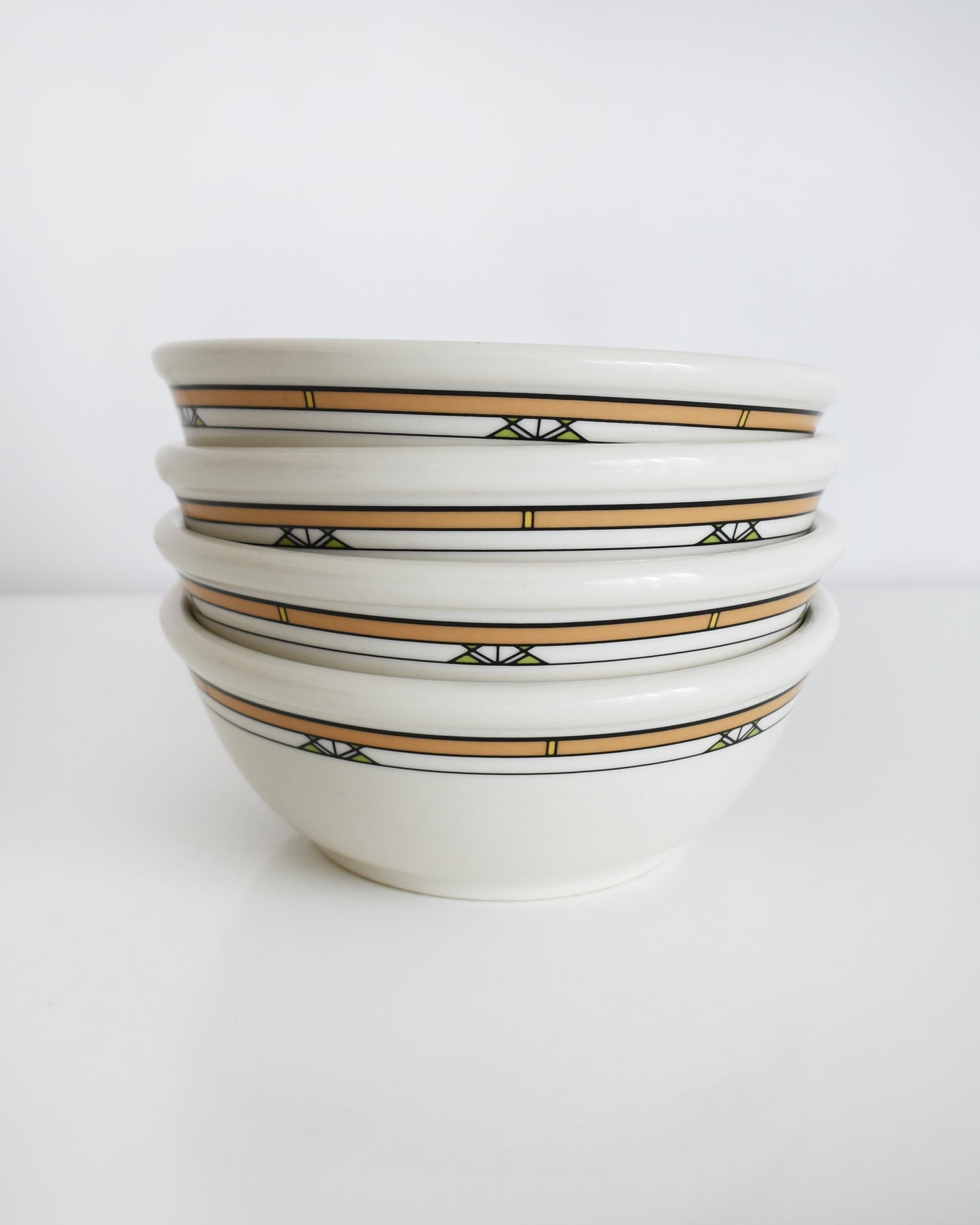a stack of Frank Lloyd Wright Martin House white bowls with brown geometric patterns on a white background