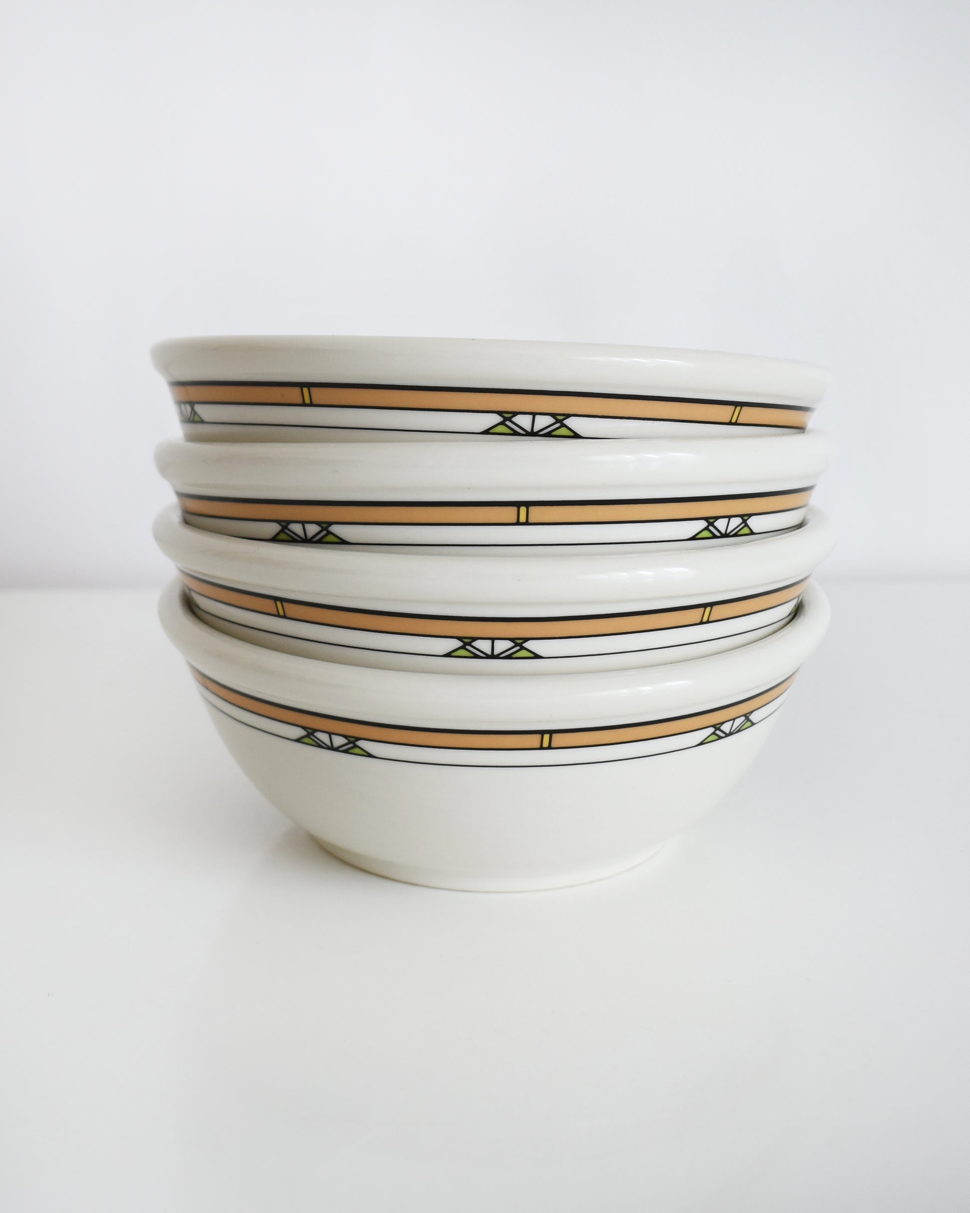 a stack of Frank Lloyd Wright Martin House white bowls with brown geometric patterns on a white background