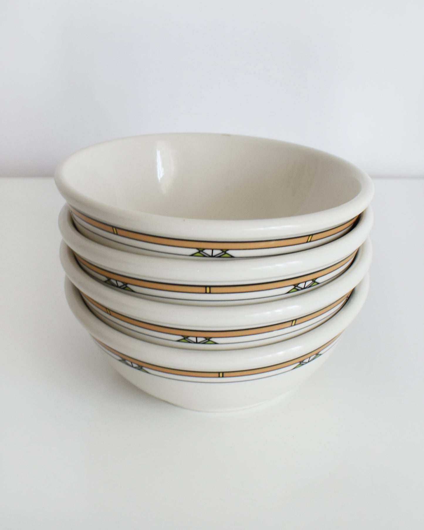 a stack of Frank Lloyd Wright Martin House white bowls with brown geometric patterns on a white background