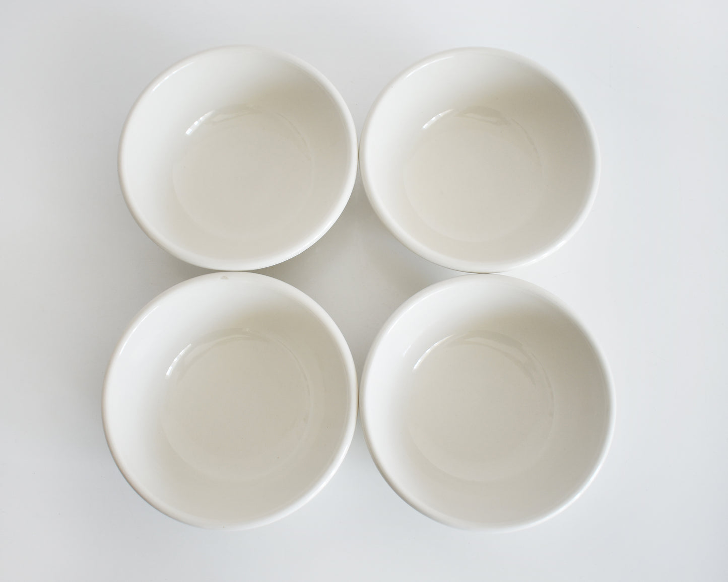 overhead shot of a set of four Frank Lloyd Wright Martin House white bowls with brown geometric patterns on a white background