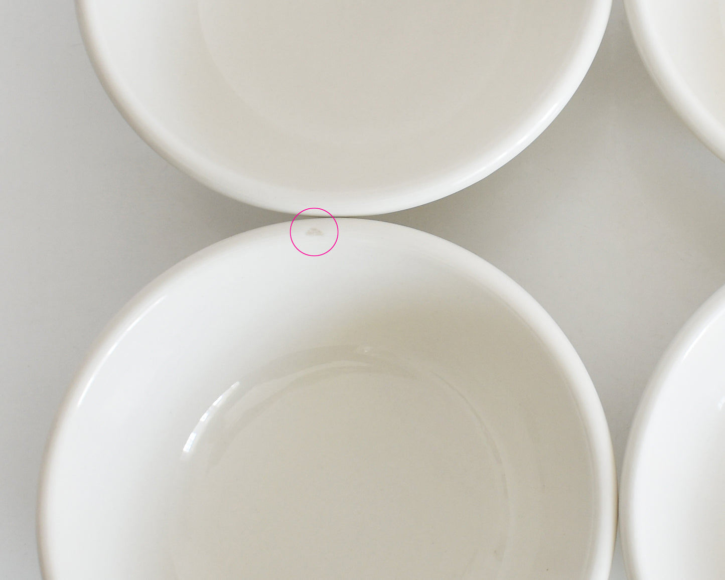 Close-up of a white ceramic bowl with a circular detail showing a small flaw on the rim