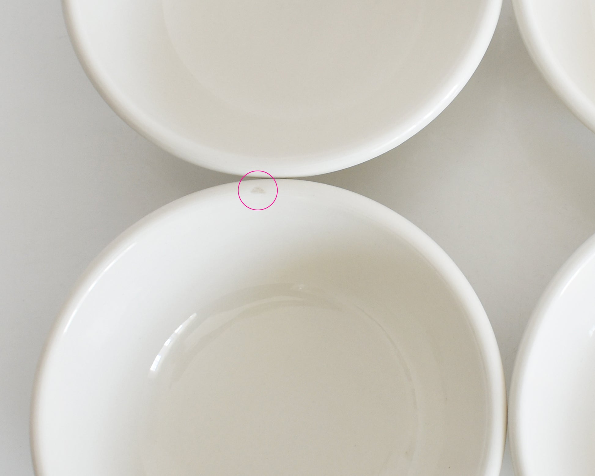 Close-up of a white ceramic bowl with a circular detail showing a small flaw on the rim
