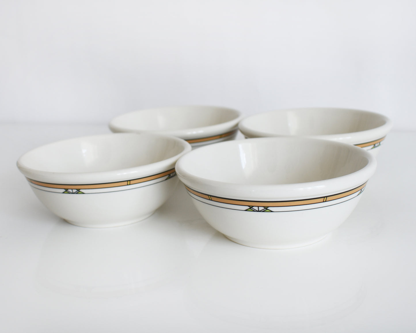 a set of four Frank Lloyd Wright Martin House white bowls with brown geometric patterns on a white background
