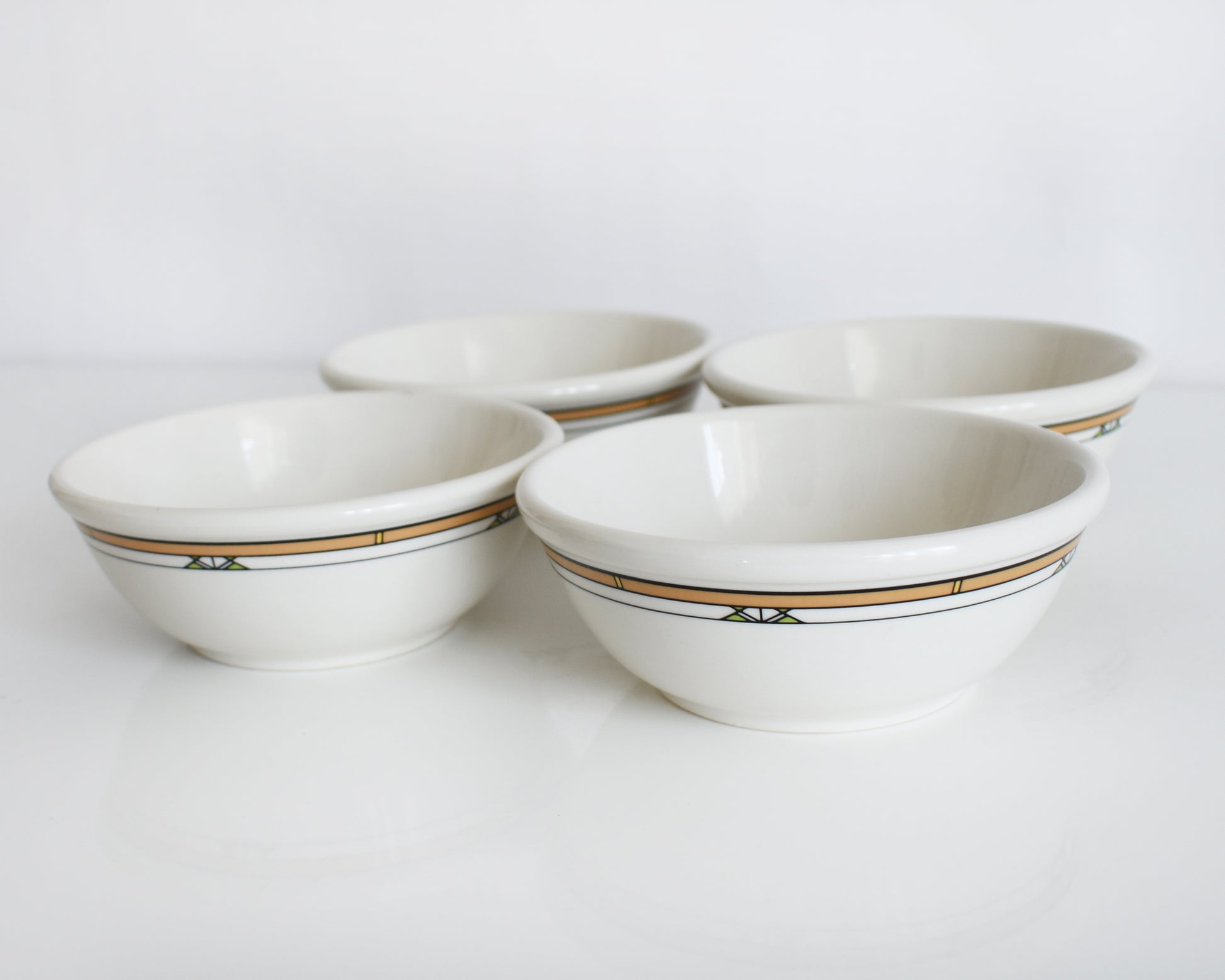 a set of four Frank Lloyd Wright Martin House white bowls with brown geometric patterns on a white background