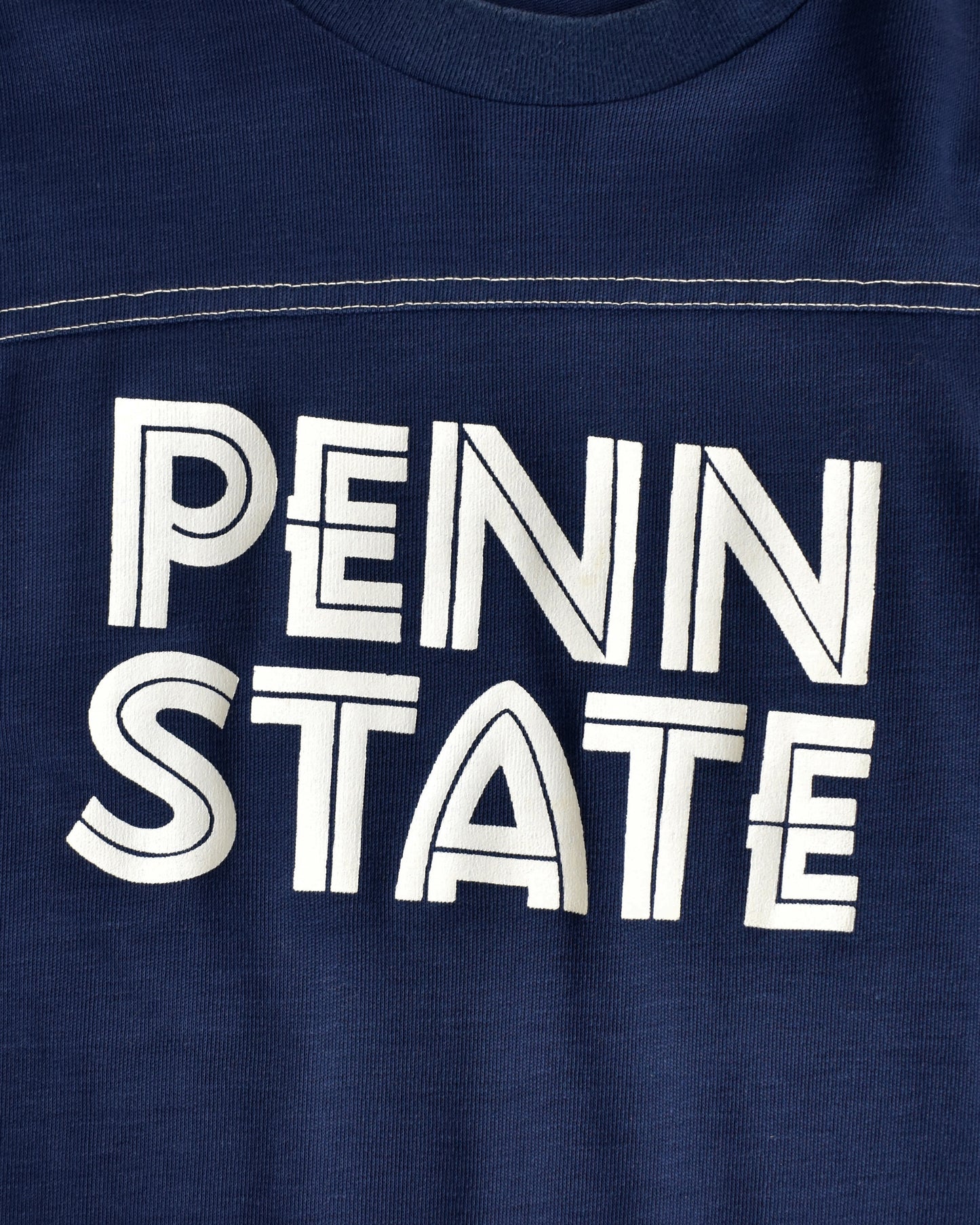 close up view of a navy blue shirt with 'PENN STATE' printed in white on a close-up view