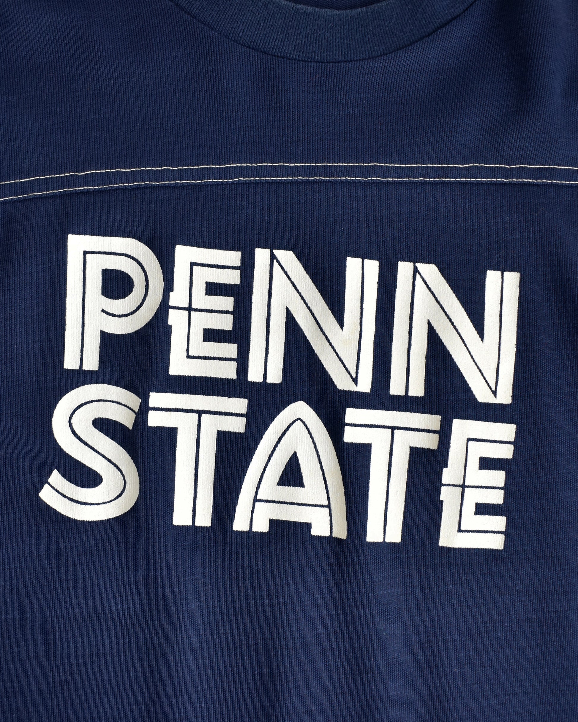 close up view of a navy blue shirt with 'PENN STATE' printed in white on a close-up view