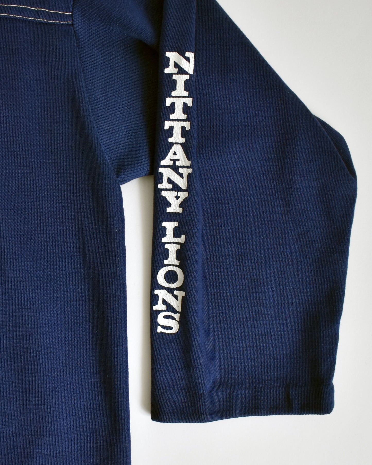 close up of a navy blue shirt with 'Nittany Lions' text on the sleeve on a white background