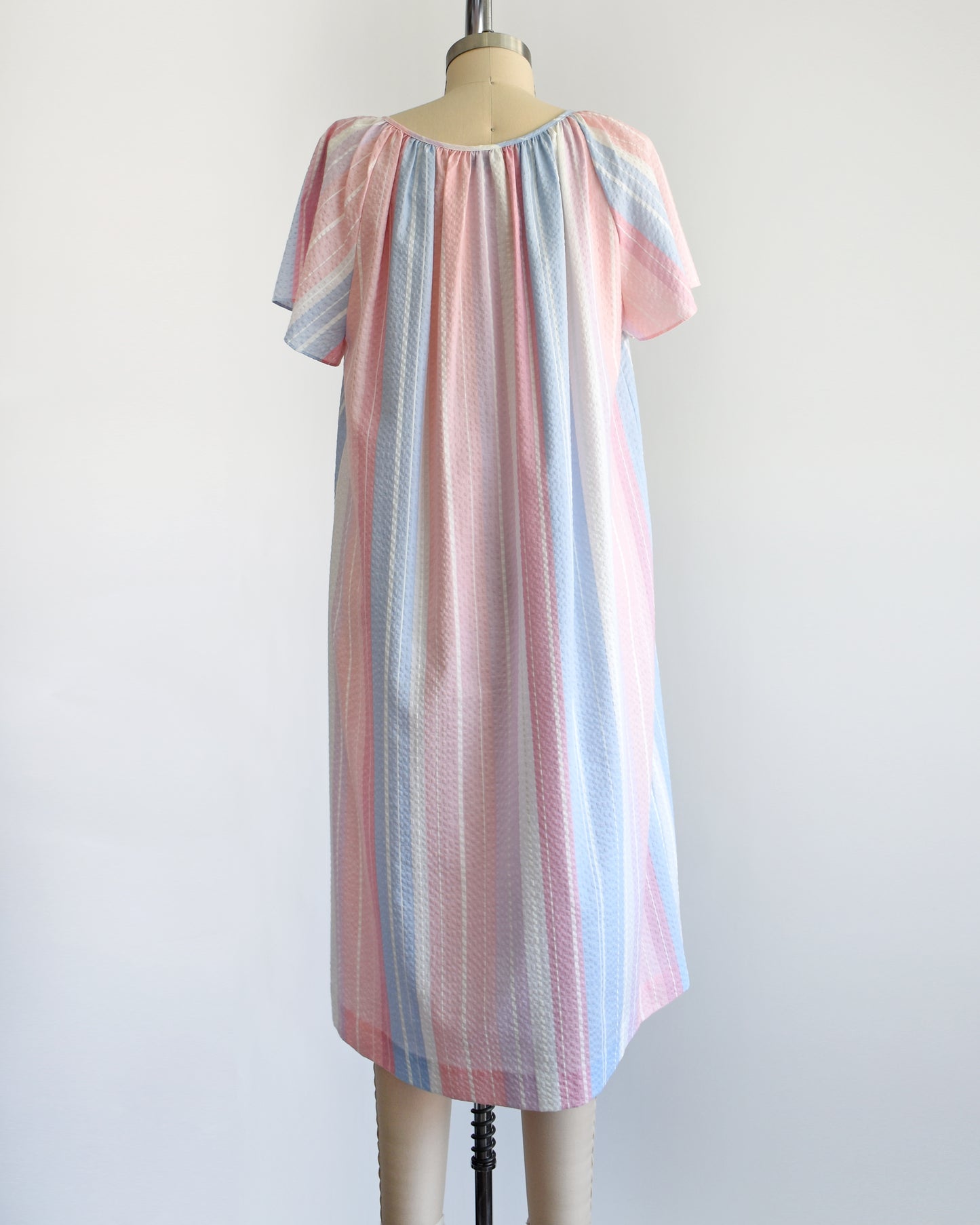 back view of a vintage 1980s blue, pink, and white striped house dress on a dress form