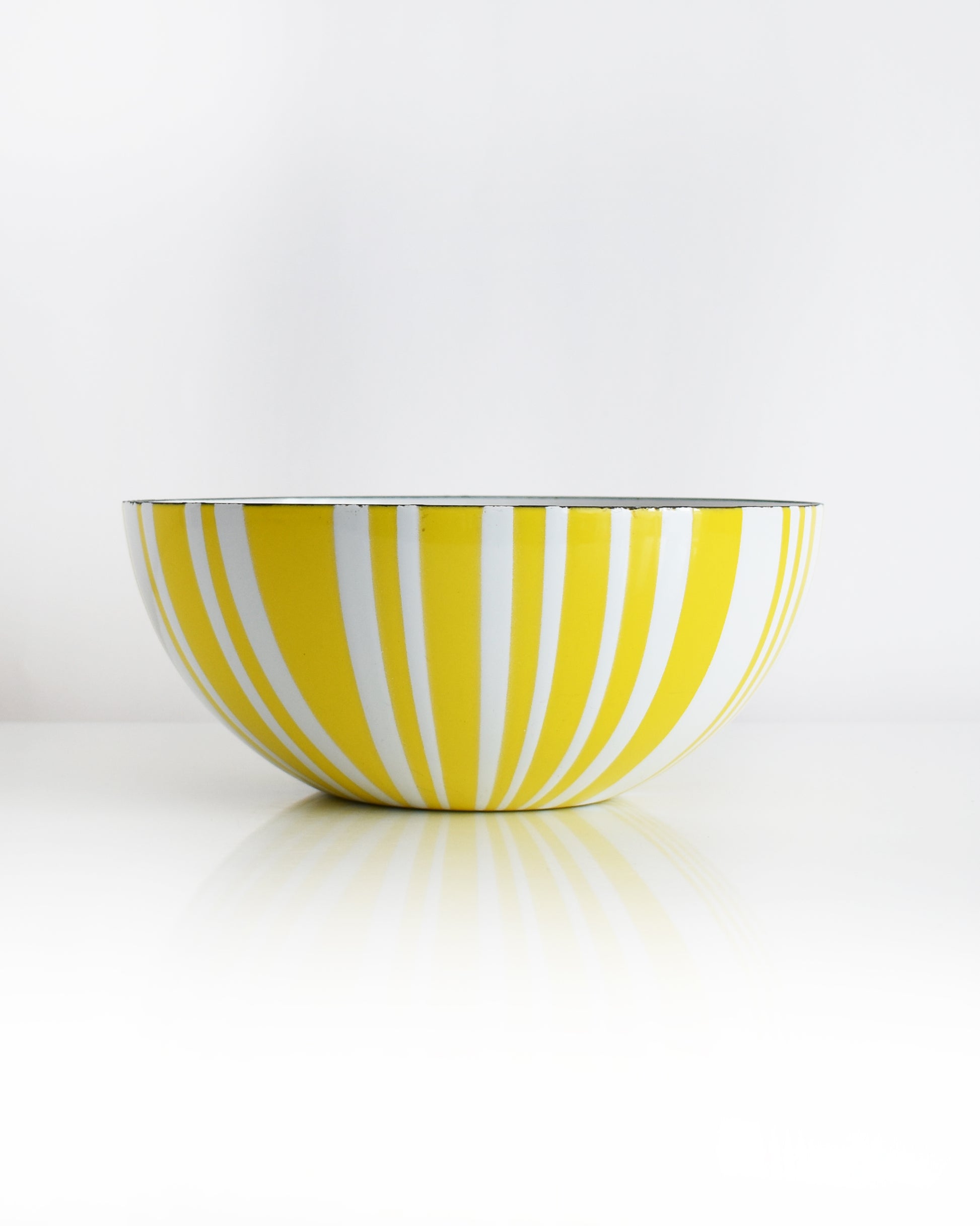 a vintage yellow and white striped Cathrineholm bowl on a white background