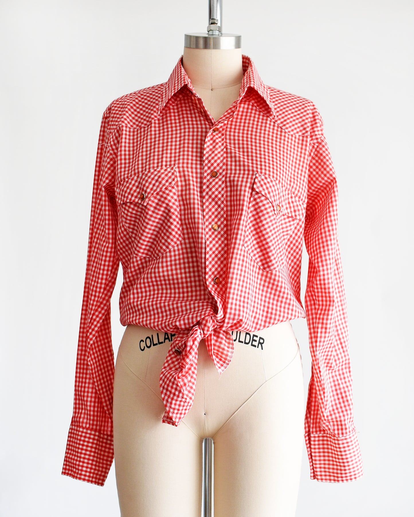 a vintage 1970s red and white gingham shirt  that's tied in the front on a mannequin against a white background