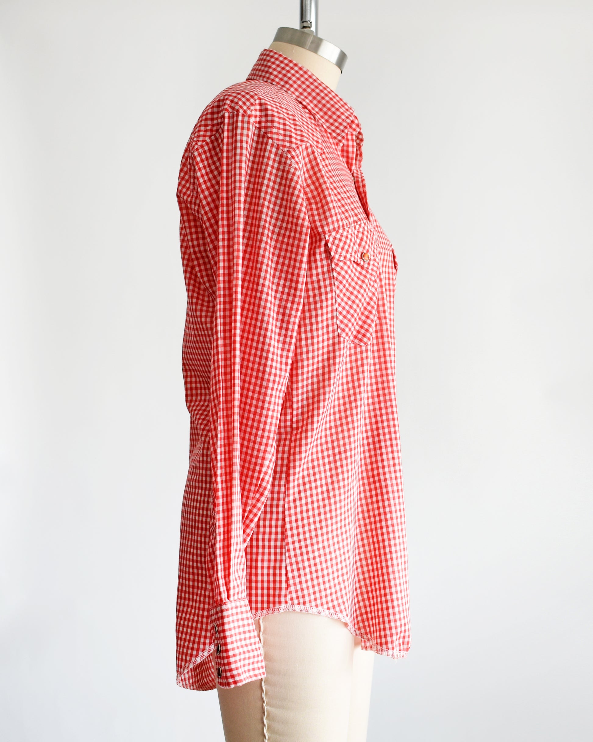 side view of a vintage 1970s red and white gingham shirt on a mannequin against a white background
