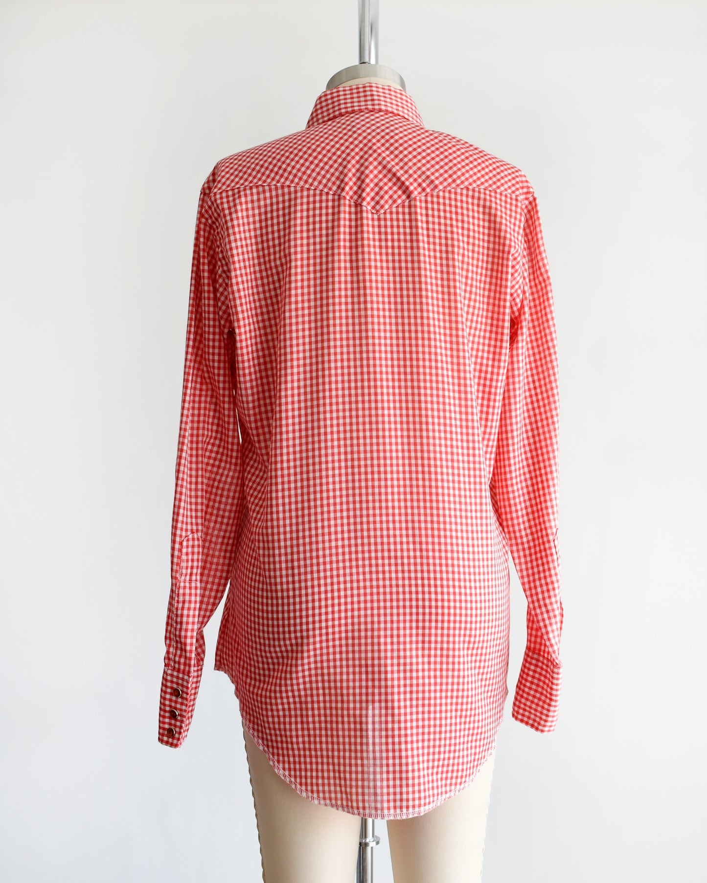 back view of a vintage 1970s red and white gingham shirt on a mannequin against a white background