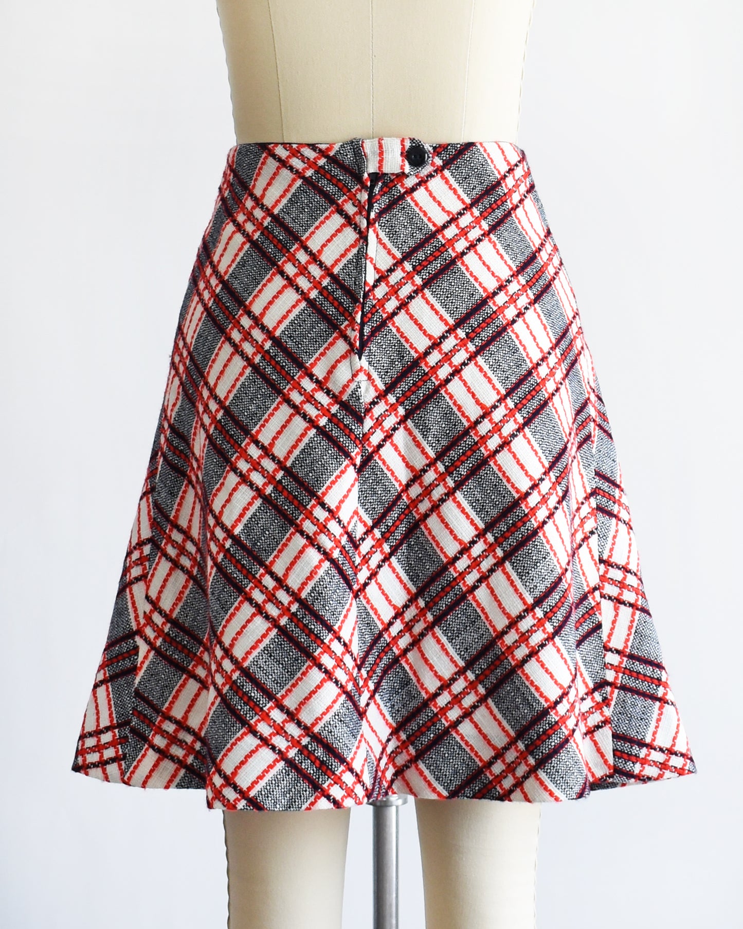 back button on a vintage plaid skirt on a mannequin against a white background
