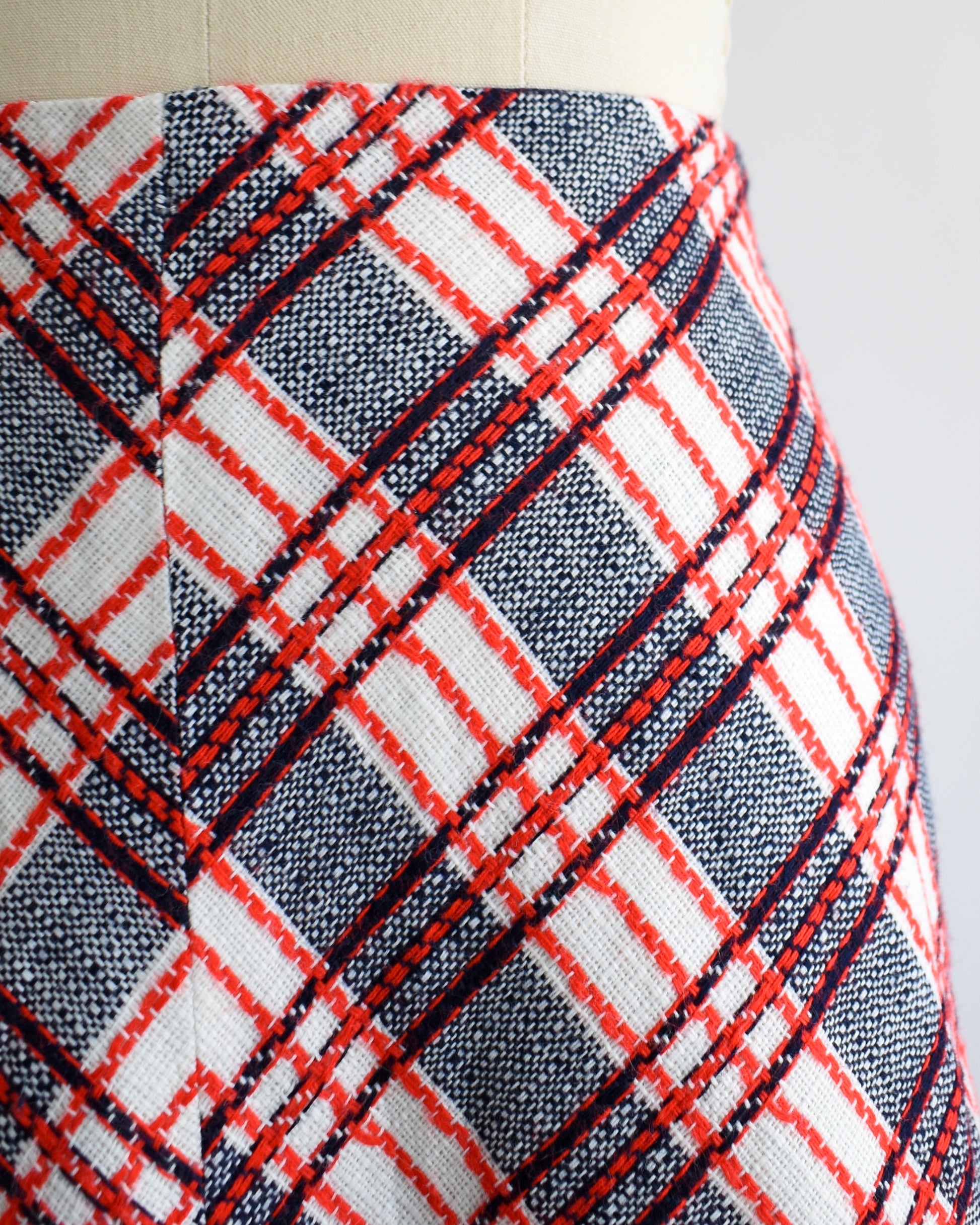 close up of a vintage plaid skirt on a mannequin against a white background
