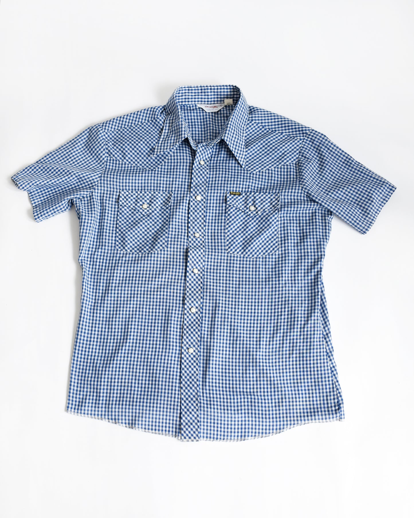 a vintage 1980s blue checkered pearl snap Wrangler shirt on a white background